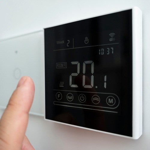 close-up of a hand adjusting a thermostat